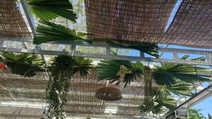 A covered outdoor area with hanging plants and a birdcage. - Sanssouci Kep (Kep)