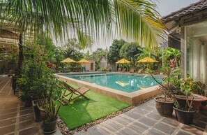 A swimming pool surrounded by potted plants and outdoor furniture. - Sanssouci Kep (Kep)