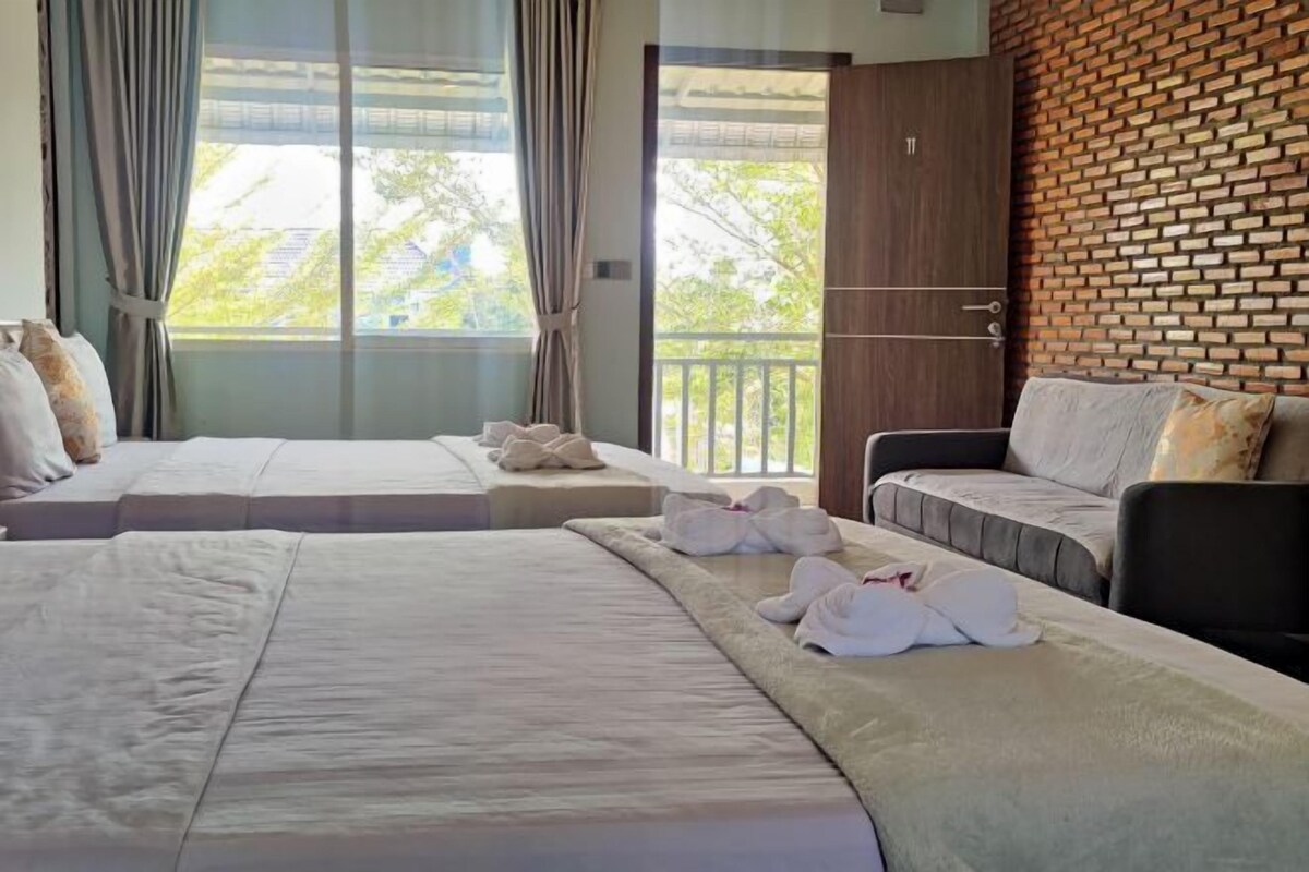 Habitación de hotel con dos camas, un balcón y una pared de ladrillo.