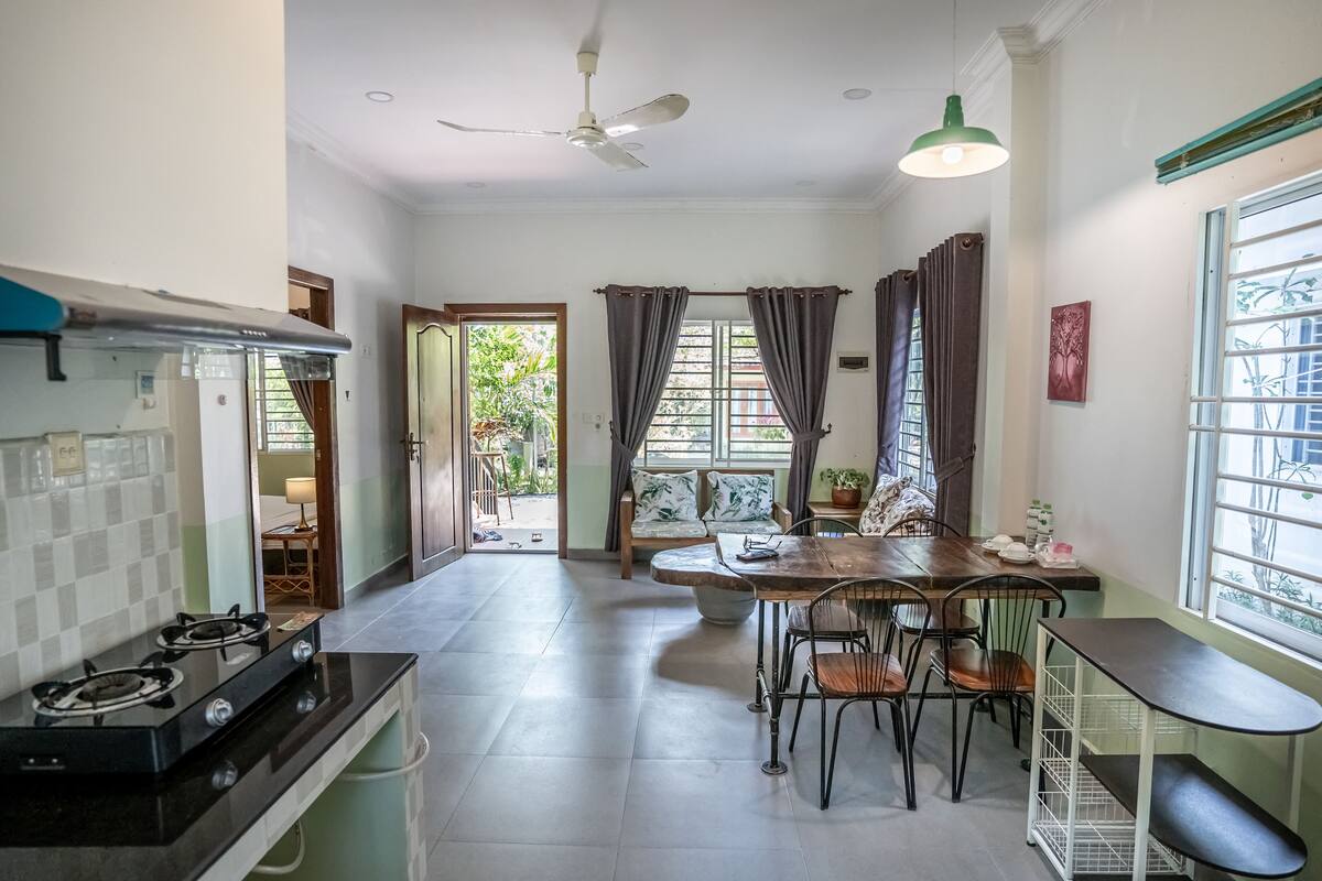 A compact kitchen with a gas stove, a dining table with chairs, and a ceiling fan.