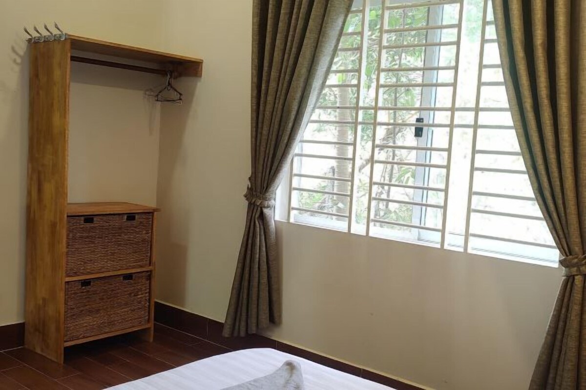 A room with a bed, a wooden wardrobe with baskets, and a window with curtains.