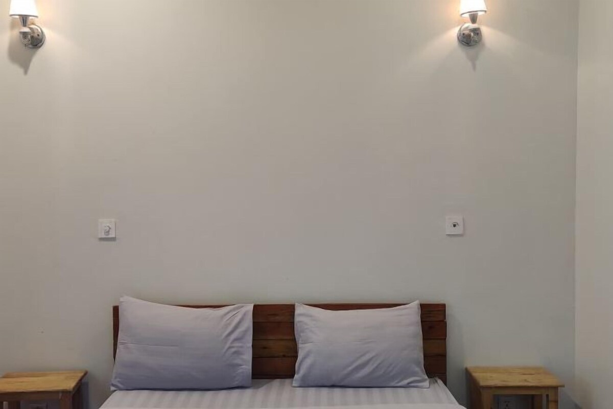 A bed with a wooden headboard, two white pillows, and two bedside tables with lamps.