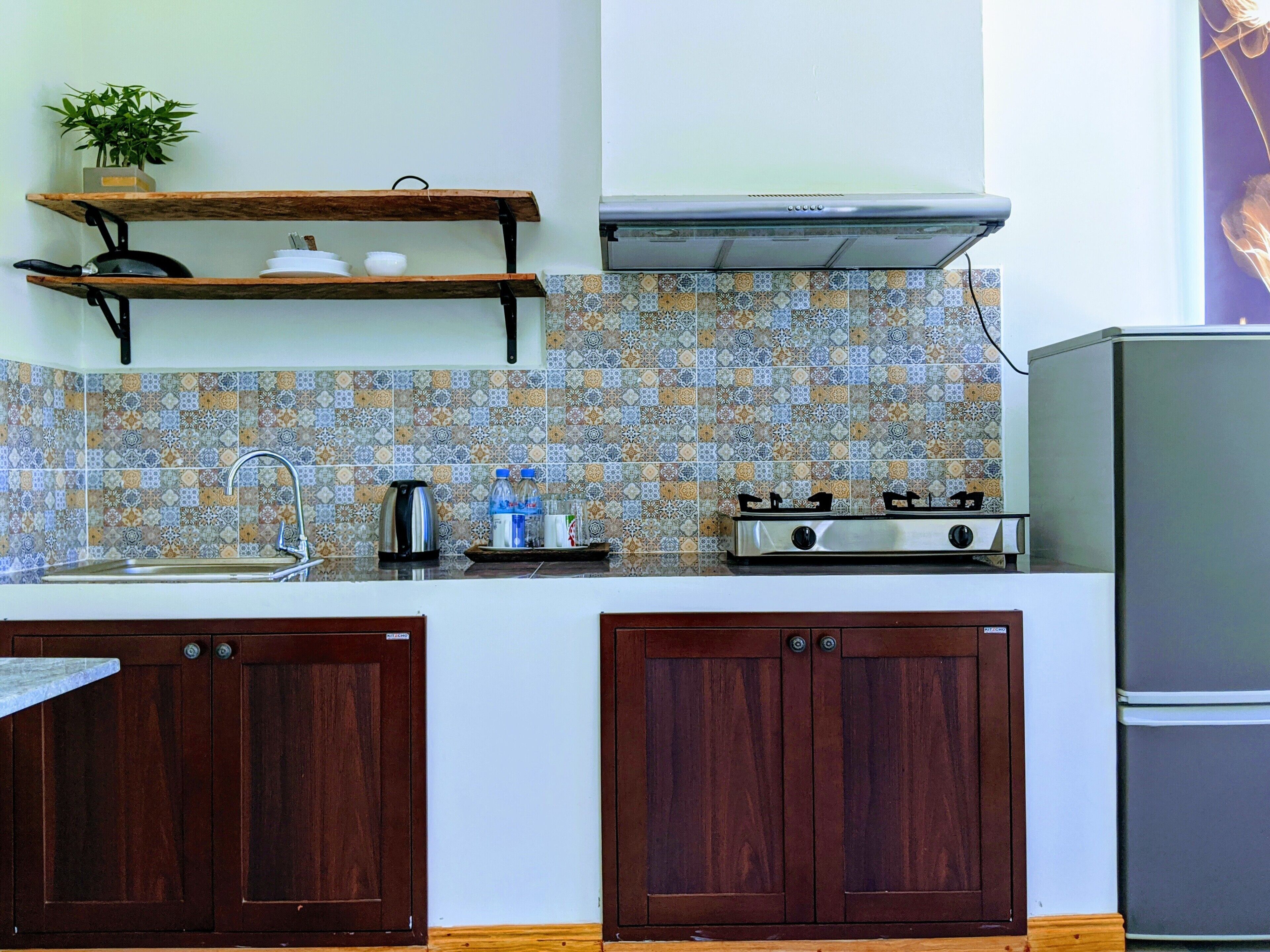Una cucina con mobili in legno, piano cottura a gas, lavello e zoccolo decorativo.