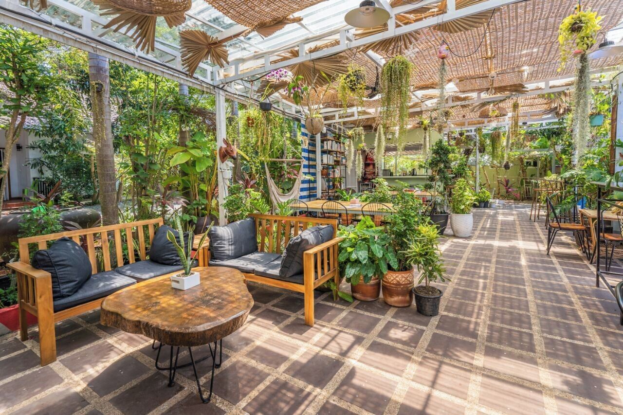 Un vaste jardin intérieur agrémenté de meubles en bois et de plantes suspendues.