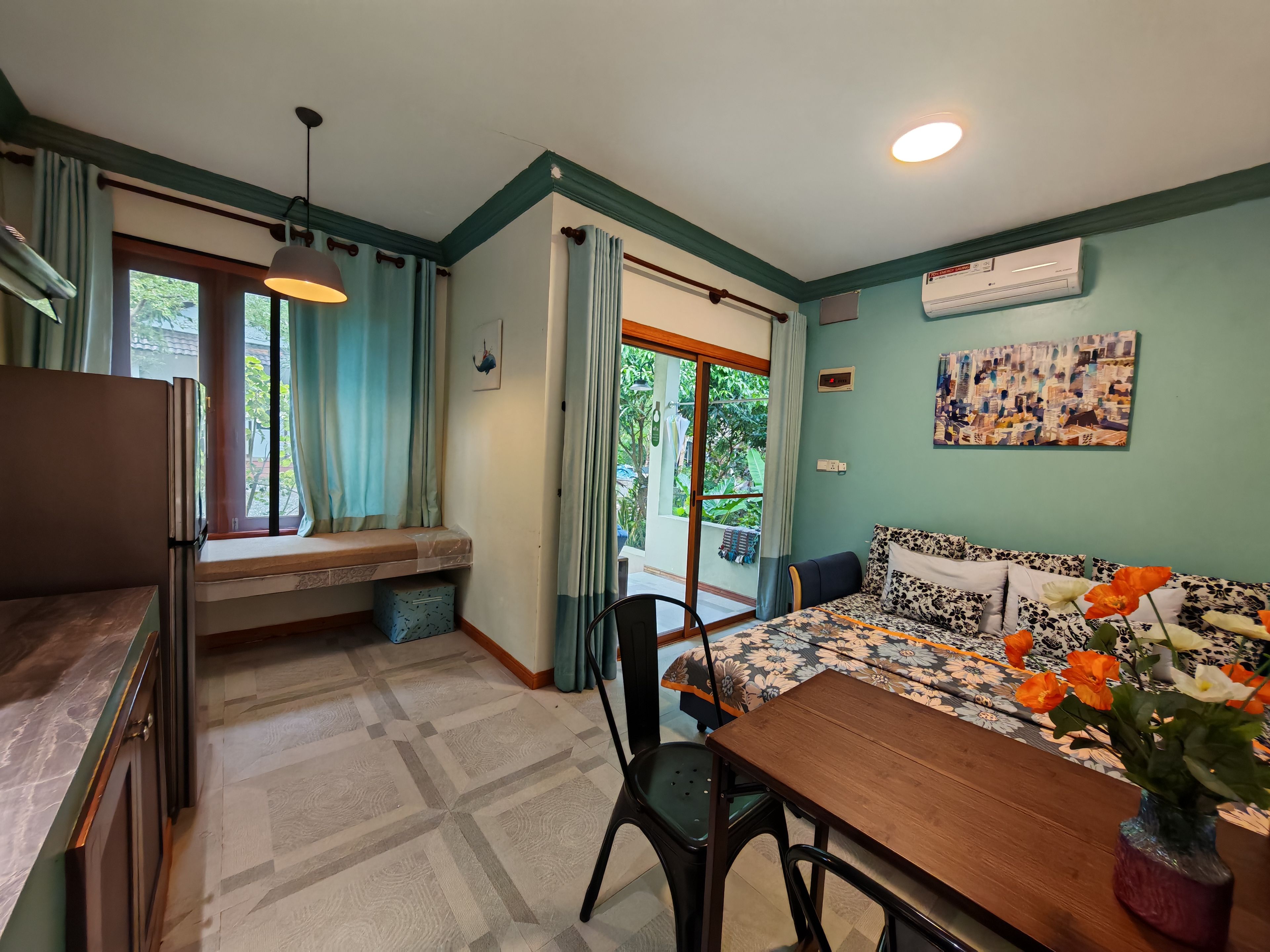 A compact room with a dining table, chairs, a bench, and a refrigerator.