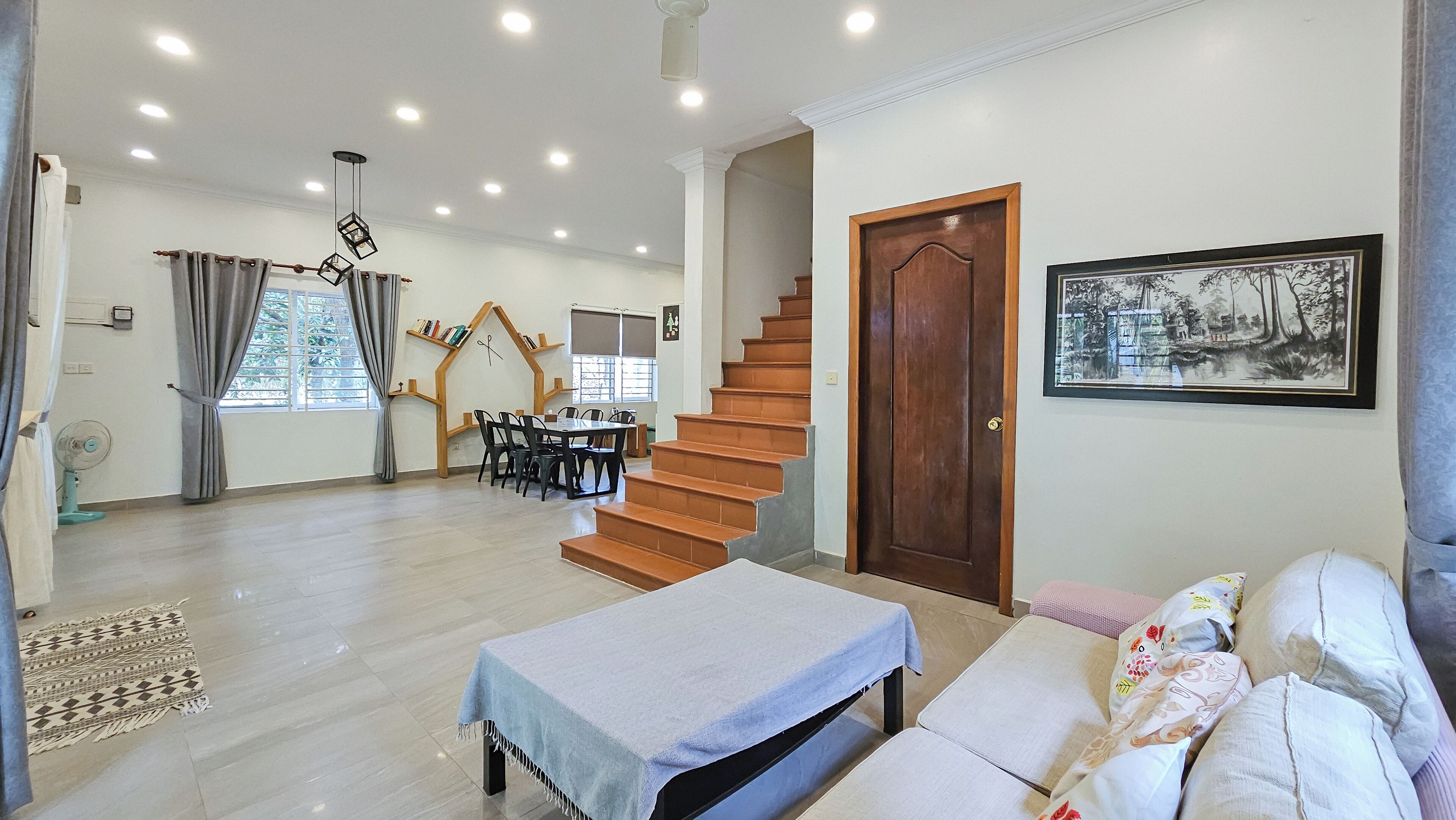 A spacious living area with a staircase, a dining table, and a sofa.