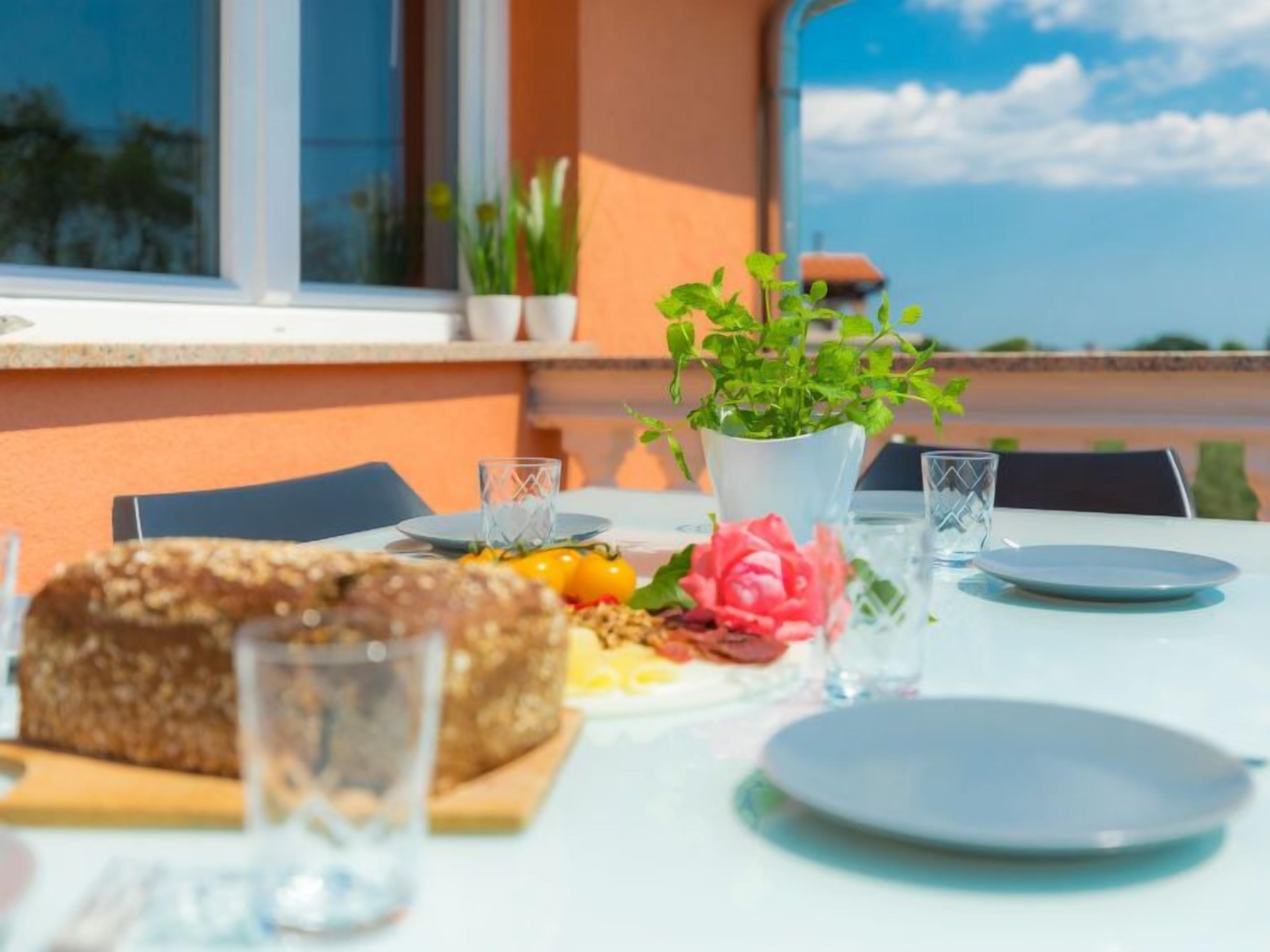 Une table dressée avec des assiettes, des verres, un pain et une plante en pot.