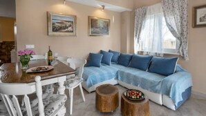 A cozy living room with a sofa, a dining table with chairs, and two wooden stools. - Villa Aurora by Interhome (Pula)