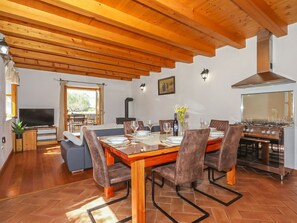 A dining area with a wooden table, chairs, and a kitchen with a stove. - Vacation home Ceko by Interhome (Zadar/Sukošan)