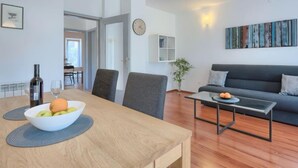 A modern living room with a sofa, a dining table with a bowl of fruit, and a coffee table. - Vacation home Gojak by Interhome (Pula)