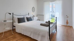 A bedroom with a bed, bedside table, lamp, and a view of the outside. - Vacation home Gojak by Interhome (Pula)