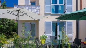 A two-story building with a balcony and a table with an umbrella. - Vacation home Gojak by Interhome (Pula)