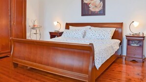A bedroom with a wooden bed, two bedside tables, a nightstand, a wardrobe, and a painting on the wall. - Vacation home Lea by Interhome (Opatija/Rukavac)