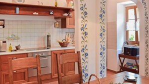 A kitchen with wooden cabinets, a tiled backsplash, and a dining area with a table set for two. - Vacation home Lea by Interhome (Opatija/Rukavac)