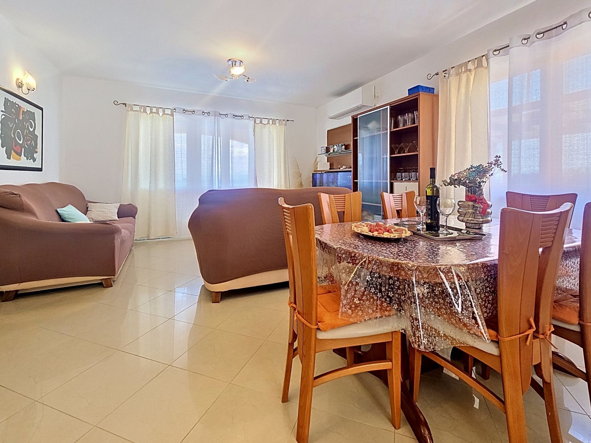 A dining area with a round table, chairs, and a buffet cabinet.