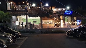 A building with a balcony and outdoor seating area, a sign indicating a one-way street, and parked cars. - Plantation springs luxury apartment (Kingston)