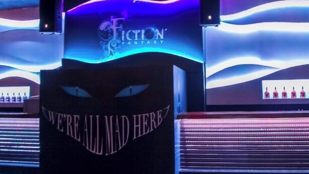 A bar area with a sign reading "Fiction Fantasy" and a counter with a sign that says "WE'RE ALL MAD HERE". - Plantation springs luxury apartment (Kingston)