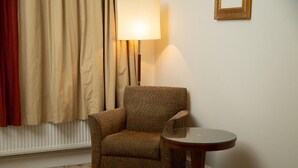 A room with a patterned carpet, a brown armchair, a small round table, a floor lamp, and a framed picture on the wall. - The Ladbrooke Hotel (Birmingham)