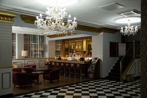 A bar area with a checkered floor, bar stools, a chandelier, and a bar counter with bottles. - The Ladbrooke Hotel (Birmingham)