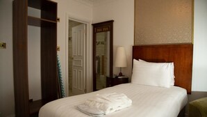 A hotel room with a large bed, a wooden wardrobe, a nightstand with a lamp, and a mirror. - The Ladbrooke Hotel (Birmingham)