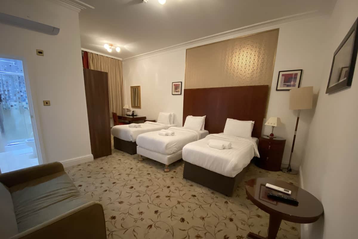 Hotellihuone, jossa on kaksi sänkyä, sohva, työpöytä ja tuoli.