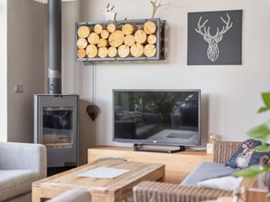 A living room with a fireplace, a television, and a wall-mounted log display.