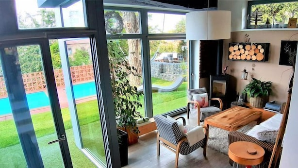 A spacious living area with a large sliding glass door leading to a backyard, a wooden dining table, and a cozy seating arrangement. - Řeporyje by Interhome (Reporyje)