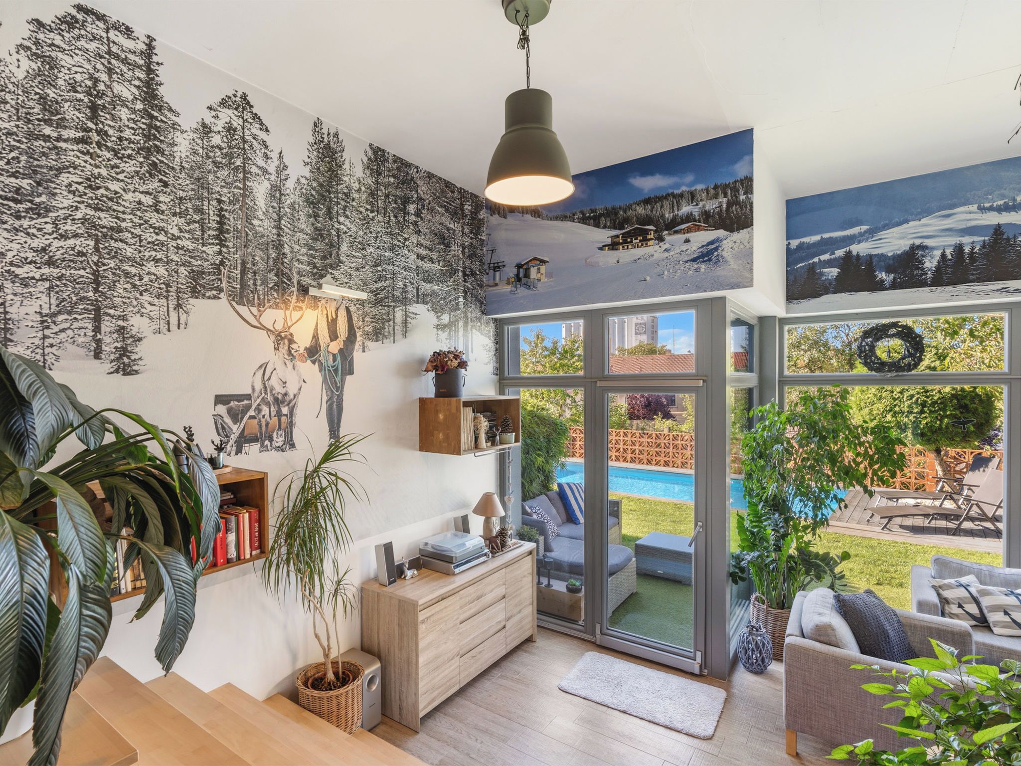 Un interior moderno con escalera, chimenea, comedor y vistas a una piscina y jardín.