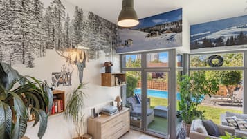 Un interior moderno con escalera, chimenea, comedor y vistas a una piscina y jardín.