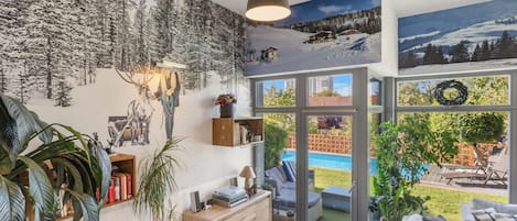Un interior moderno con escalera, chimenea, comedor y vistas a una piscina y jardín.