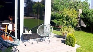A modern outdoor deck with two chairs, a table, and a glass door leading to a patio area. - Řeporyje by Interhome (Reporyje)