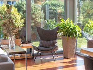 A modern interior with a large window, a grey upholstered chair, and a potted plant.