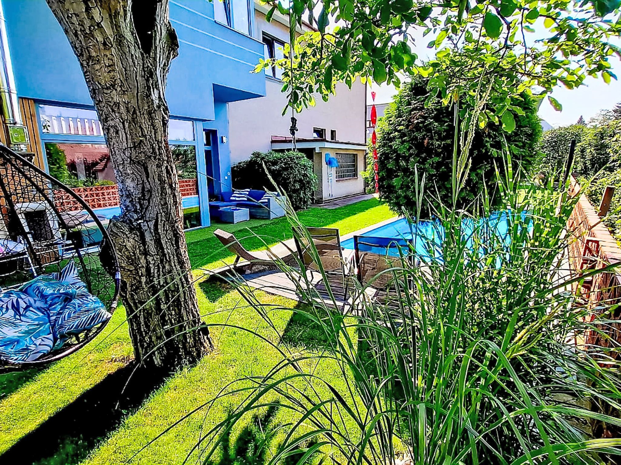 A modern outdoor seating area with a tree, a blue building, and a pathway.