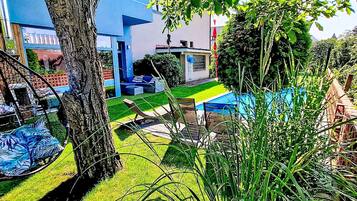 A modern outdoor seating area with a tree, a blue building, and a pathway.