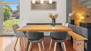 Un comedor moderno con una mesa de madera, cuatro sillas e iluminación colgante.