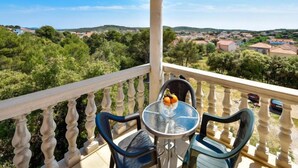 Ein Balkon mit Tisch und Stühlen mit Blick auf eine malerische Landschaft mit Bäumen und Gebäuden.