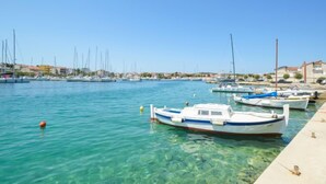 Ein Yachthafen mit mehreren angedockten Booten, klarem Wasser und Gebäuden im Hintergrund.