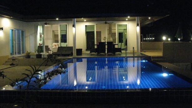 Ein modernes Haus mit Schwimmbad bei Nacht.