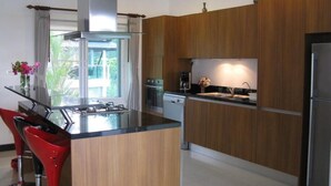 Eine moderne Küche mit Holzschränken, einem Edelstahlkühlschrank und einer zentralen Kochinsel mit Spüle.