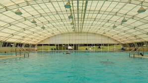 Ein Innenpool mit hoher, gewölbter Decke und mehreren Sprungbrettern.