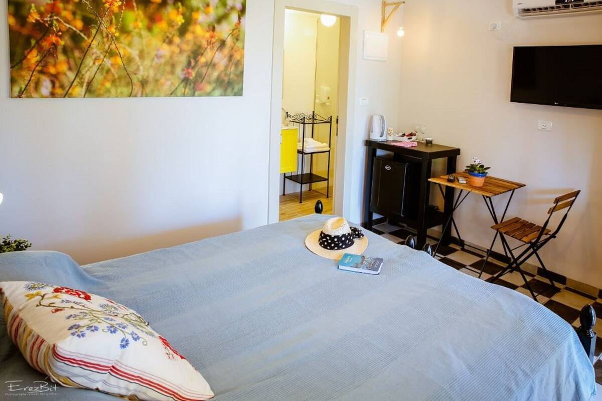 A bedroom with a bed, a desk, a chair, and a television on the wall.