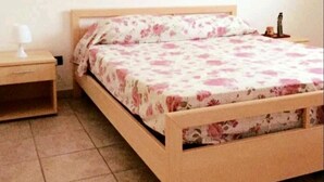 Un dormitorio con cama de madera, mesita de noche, lámpara y un cuadro en la pared.