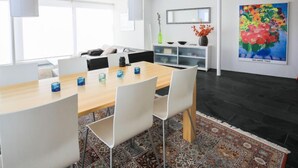 Un comedor moderno con una mesa de madera, sillas blancas e iluminación colgante.