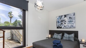 Una camera da letto moderna con un letto grande, vista sull'esterno, una scala e un lampadario.