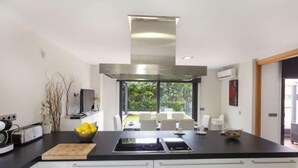Una cucina moderna con isola centrale, mobili bianchi e vista su una sala da pranzo.