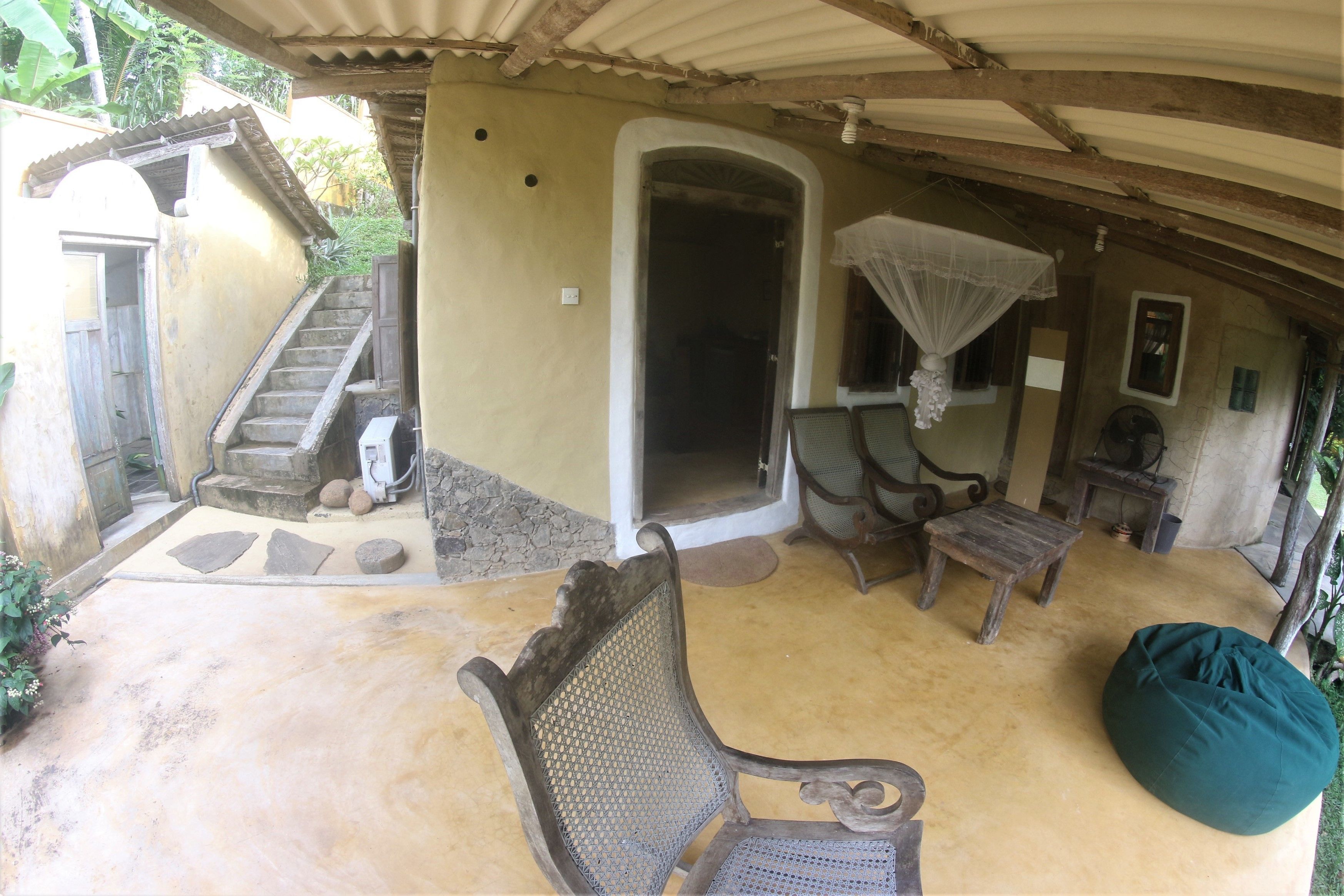 An outdoor patio with rustic furniture, a covered seating area, and a staircase leading to an upper level.