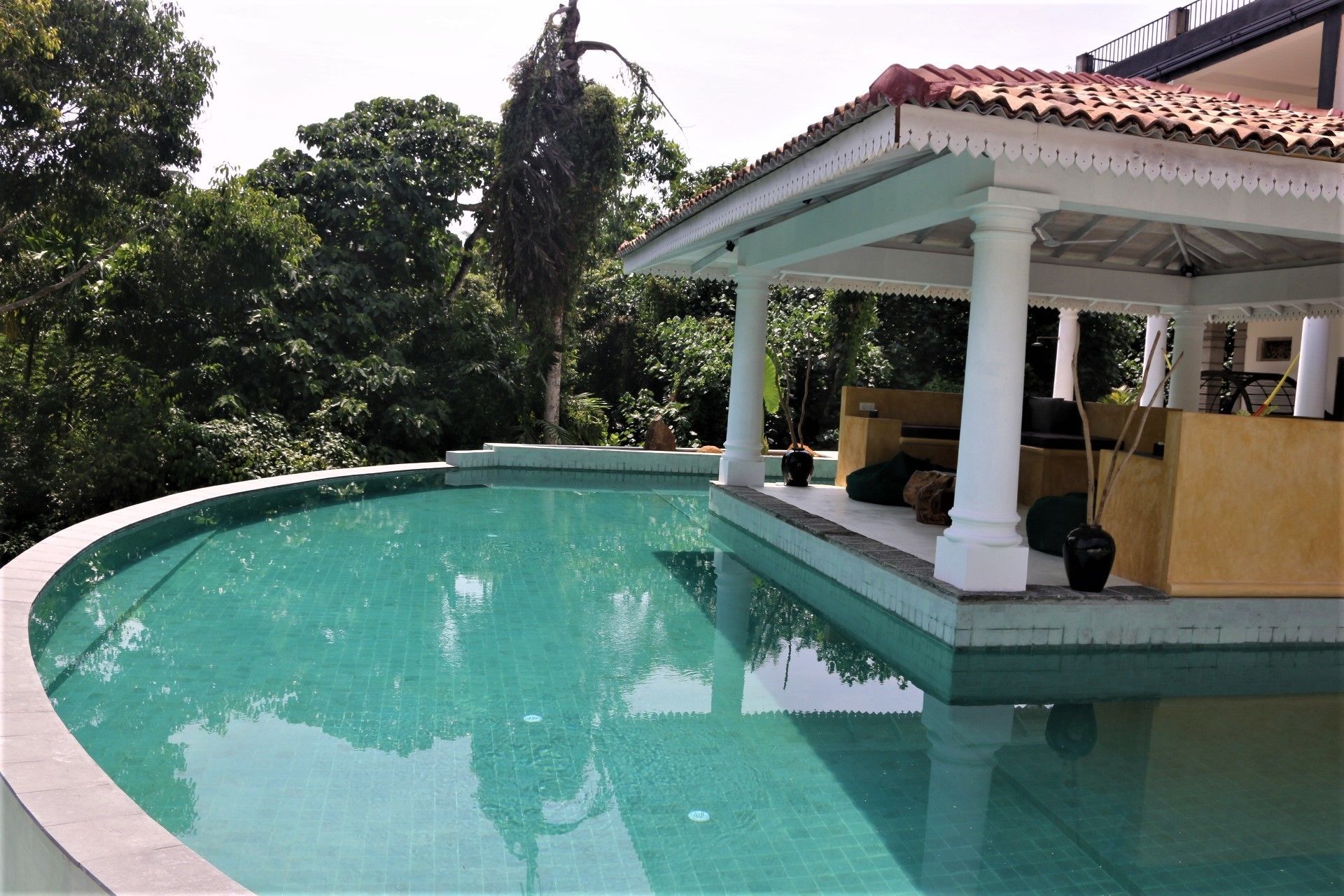 A swimming pool with a covered seating area and a pergola.