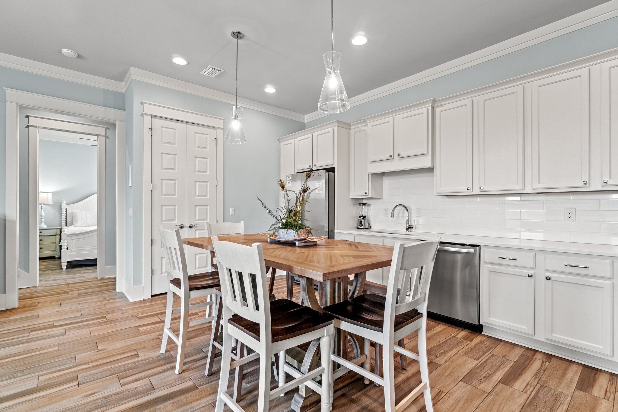 A modern kitchen with white cabinets, a wooden dining table, and a dishwasher.