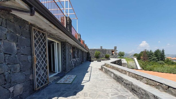 A stone building with a balcony, a stone pathway, and a view of the landscape.