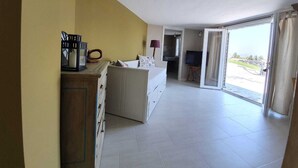 A room with a bed, a desk, a television, and a sliding glass door leading to a balcony.